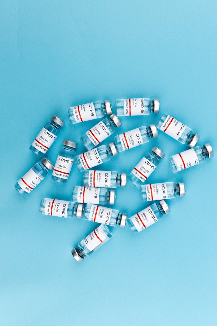 Top view of multiple Covid-19 vaccine vials on a blue background emphasizing vaccination effort.